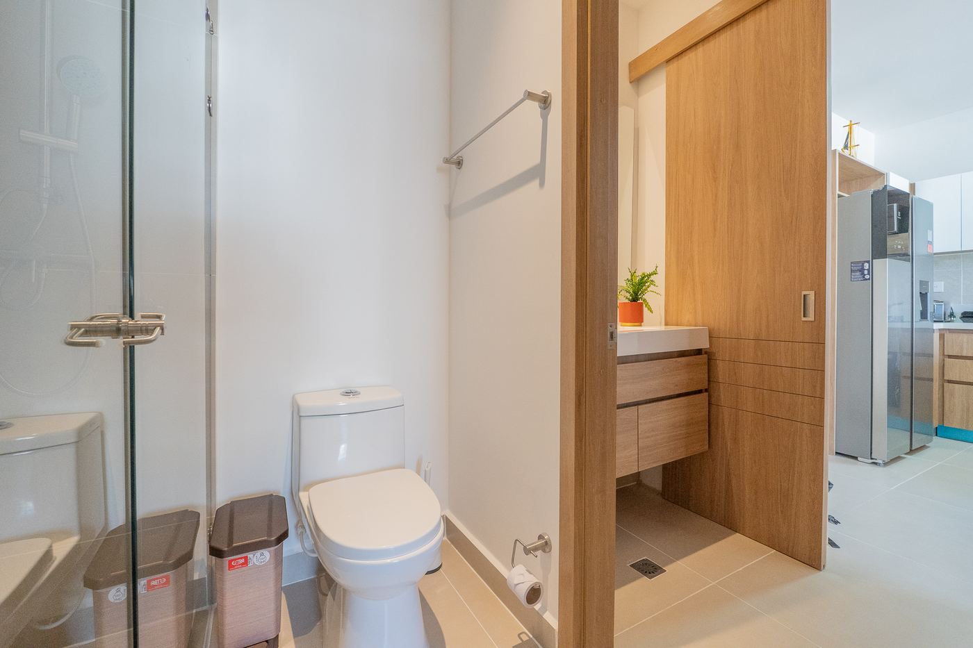 Baño con ducha de vidrio y acceso directo a la cocina