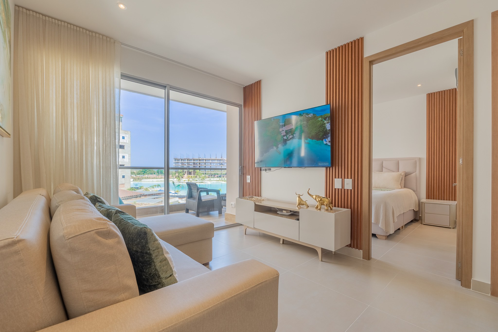Sala de estar con TV conectada a la habitación, ambas con vista a la Crystal Lagoon